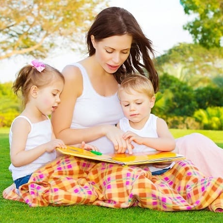 Mother and kids reading book outside